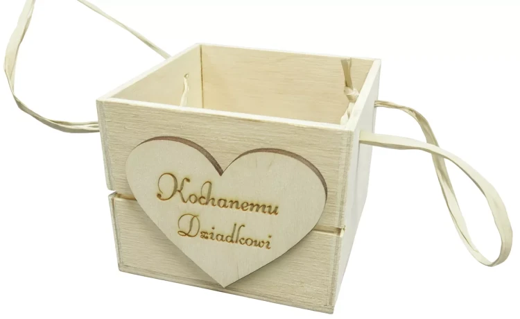 Drewniane pudełko z napisem „Kochanemu Dziadkowi” na serduszku z przodu, ozdobione wstążkami po bokach. Prosty, rustykalny design sprawia, że idealnie nadaje się jako prezent z okazji Dnia Dziadka lub innej rodzinnej uroczystości.