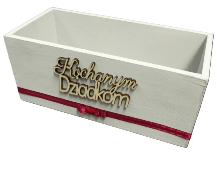 Białe drewniane pudełko z napisem „Kochanym Dziadkom”, ozdobione czerwoną wstążką z kokardką i serduszkiem. Personalizowany prezent dla dziadków na każdą okazję.