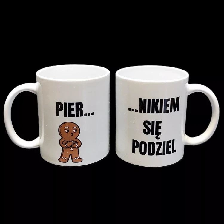 Biały ceramiczny kubek z nadrukiem „Pier... nikiem się podziel"  i grafiką piernikowego zawadiaki – śmieszny gadżet do kawy