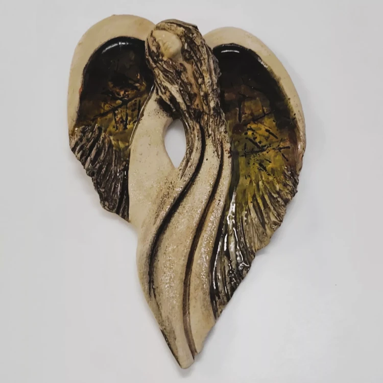 Gipsowy anioł o stylizowanej sylwetce, ręcznie malowany w odcieniach zieleni i brązu. Skrzydła tworzą kształt serca, a płynne linie i faktura nadają mu artystyczny, naturalny charakter. Utrzymany w tonacji ochrony i miłości.