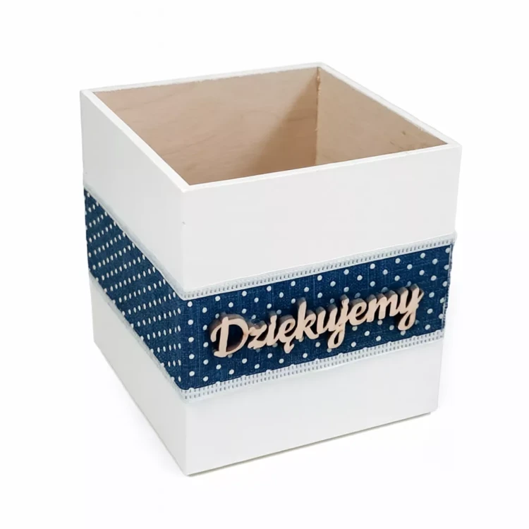 Biały, drewniany pojemnik o otwartym wierzchu, ozdobiony granatową wstążką w białe kropki. Na środku znajduje się drewniany napis „Dziękujemy”. Estetyczny i funkcjonalny, idealny jako dekoracja lub opakowanie na podziękowania.