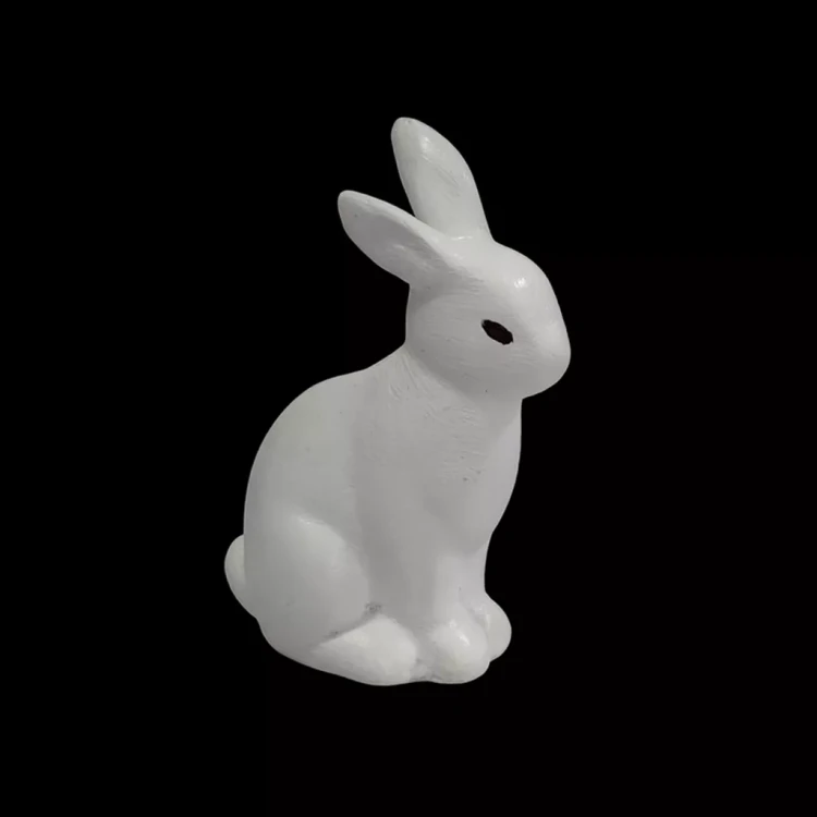 Minimalistyczna figurka beżowego zająca w pozycji siedzącej, z prostymi liniami, matową fakturą i delikatnie zaznaczonymi oczami, idealna jako dekoracja wnętrza.