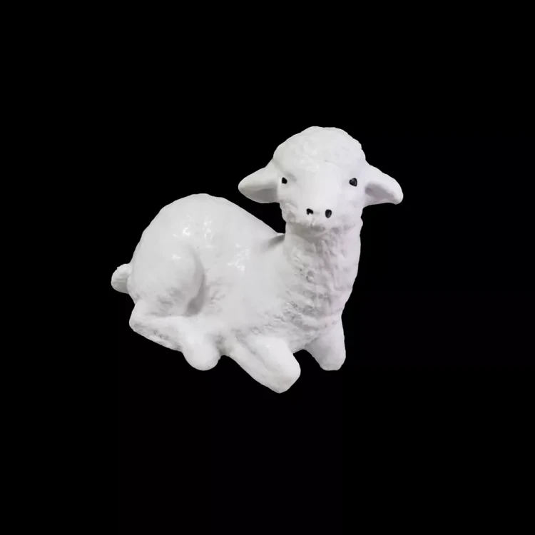 Biała figurka leżącego barana na czarnym tle, o zaznaczonych czarnymi kropkami oczach oraz nozdrzach.