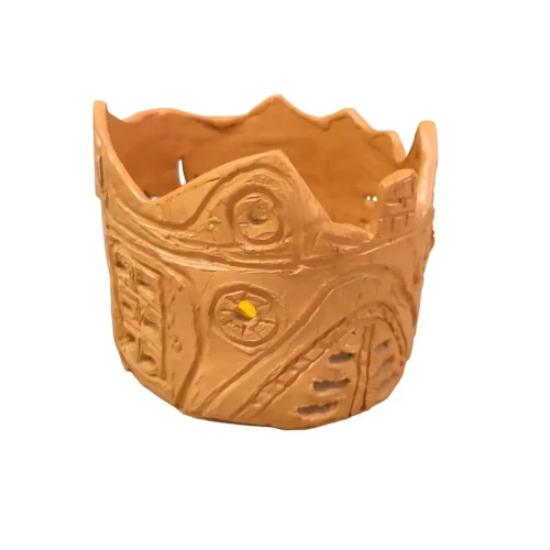 Osłonka ceramiczna w kolorze terakoty, ręcznie zdobiona o nieregularnej krawędzi i dekoracyjnych żółtych akcentach, przypominająca miniaturową architekturę.