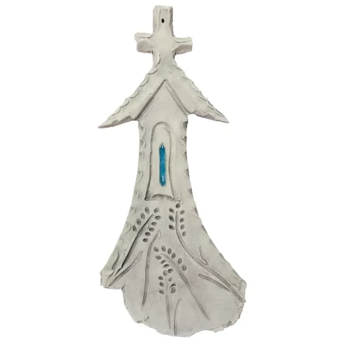 Ceramiczna kapliczka z krzyżem na szczycie, niebieskim okienkiem i roślinnymi wzorami, wykonana ręcznie z gliny, przedstawiona na białym tle jako dekoracyjny element o charakterze religijnym i symbolicznym.