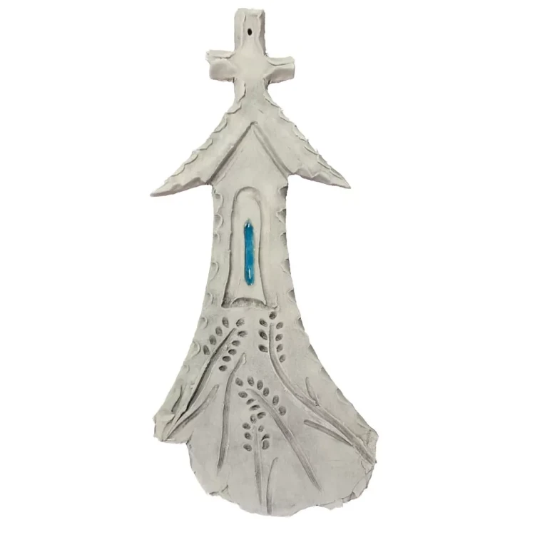 Ceramiczna kapliczka z krzyżem na szczycie, niebieskim okienkiem i roślinnymi wzorami, wykonana ręcznie z gliny, przedstawiona na białym tle jako dekoracyjny element o charakterze religijnym i symbolicznym.