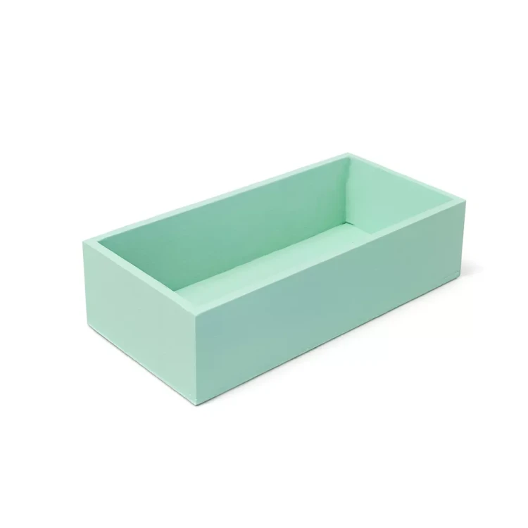 Prostokątny pojemnik w kolorze miętowym, wykonany z drewna, o otwartej górze. Jego minimalistyczny design sprawia, że doskonale sprawdza się jako organizer na biurku lub dyskretny element dekoracyjny w nowoczesnym wnętrzu.