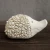 Ceramiczna figurka jeża o gładkim pyszczku i dwóch małych otworach jako oczy, z grzbietem pokrytym licznymi spiralnymi wypustkami przypominającymi kolce, ustawiona na drewnianej powierzchni.