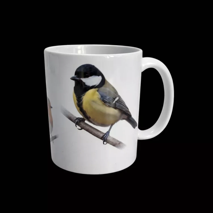 Biały ceramiczny kubek z realistyczną ilustracją sikorki bogatki siedzącej na gałęzi, na czarnym tle.
