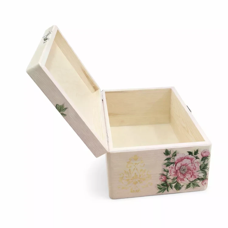 Jasna drewniana skrzyneczka z otwartą pokrywą, ozdobiona dużym różowym kwiatem, zielonymi liśćmi i żółtym wzorem z przodu, prezentująca puste wnętrze z widocznym naturalnym usłojeniem.