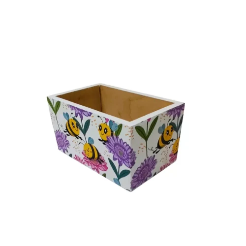 Prostokątne drewniane pudełko z otwartą górą, ozdobione decoupage w motyw pszczół i kolorowych kwiatów na białym tle; wnętrze surowe, naturalne drewno.