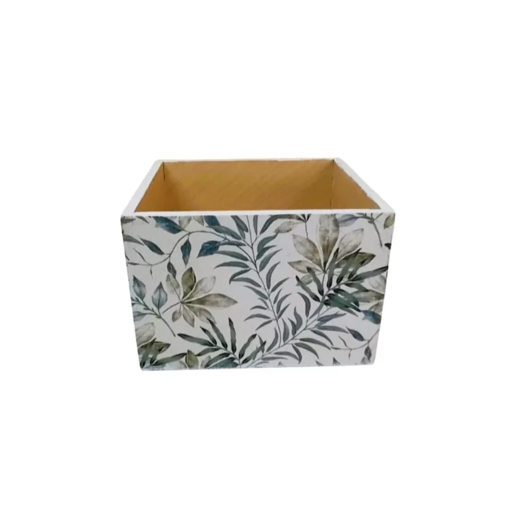 Drewniana skrzynka z otwartą górą, z zewnątrz pokryta wzorem zielonych liści. Wnętrze pozostaje proste, jasne i naturalne.
