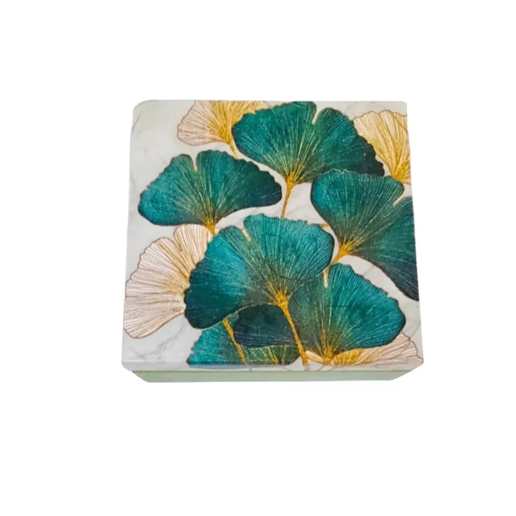 Kwadratowe drewniane pudełko z jasną pokrywką ozdobioną motywem liści miłorzębu w odcieniach ciemnej zieleni, złota i beżu, tworzących elegancki, dekoracyjny wzór.