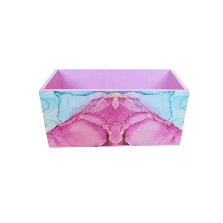 Drewniane pudełko z kolorowym, płynnym wzorem farb akwarelowych i różowym środkiem, widoczne z góry.