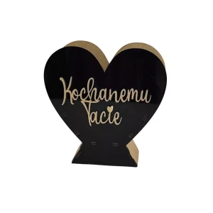 Drewniane serce stojące na podstawce, front z czarnej pleksi. Na środku naklejony złoty napis „Kochanemu Tacie” w ozdobnej czcionce. Prosta dekoracja w formie upominku dla ojca.