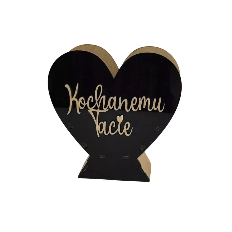 Drewniane serce stojące na podstawce, front z czarnej pleksi. Na środku naklejony złoty napis „Kochanemu Tacie” w ozdobnej czcionce. Prosta dekoracja w formie upominku dla ojca.