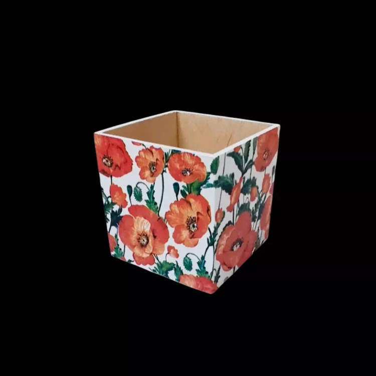 Drewniane pudełko w kształcie sześcianu bez wieczka. Zewnętrzne boki zdobią ilustracje czerwonych maków na białym tle. Klasyczny motyw florystyczny, wyraźne kolory, wnętrze w kolorze sosny. Widok z perspektywy z góry.