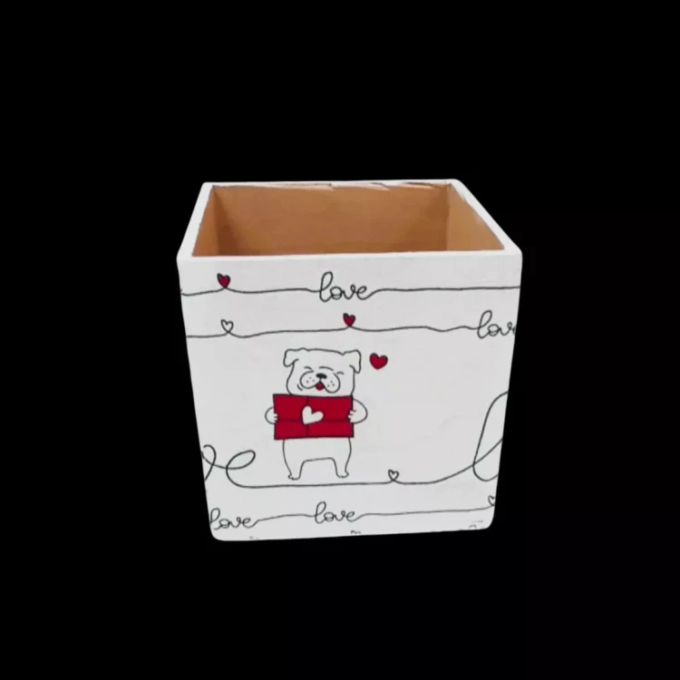 Białe drewniane pudełko z bliska. Na froncie rysunek białego buldoga trzymającego czerwony list z sercem. Powyżej i poniżej czarne linie z napisem Love i małymi serduszkami. Wnętrze pudełka w naturalnym kolorze drewna. Tło czarne.