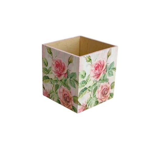 Kwadratowe pudełko z jasnego drewna, ozdobione techniką decoupage. Na zewnętrznych ściankach widoczny wzór różowych róż z zielonymi liśćmi na jasnym tle, wnętrze gładkie, naturalne.