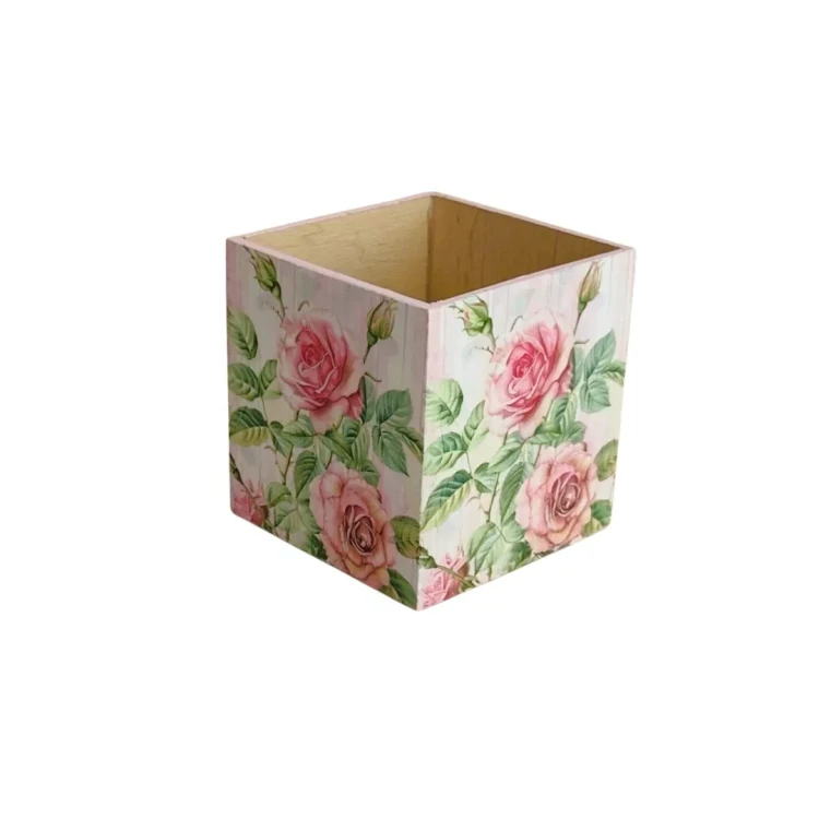 Kwadratowe pudełko z jasnego drewna, ozdobione techniką decoupage. Na zewnętrznych ściankach widoczny wzór różowych róż z zielonymi liśćmi na jasnym tle, wnętrze gładkie, naturalne.