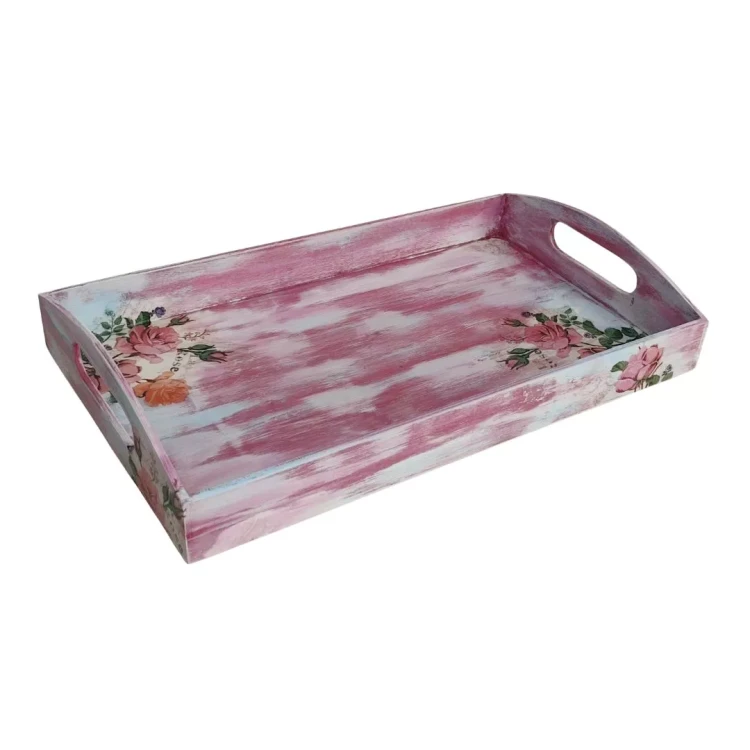 Drewniana taca decoupage z motywem róż, ujęta pod kątem z góry. Widoczne podłużne, przetarte pasy różowej i białej farby na dnie oraz bokach. Konstrukcja ma wycięte owalne uchwyty na dłonie.